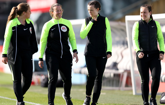 Four match officials walking on a pitch